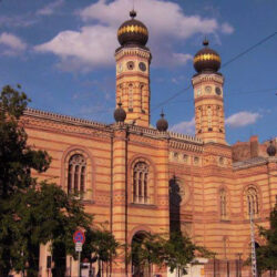 Tiene dos altas torres laterales con reloj, y sendas cúpulas características de las sinagogas.